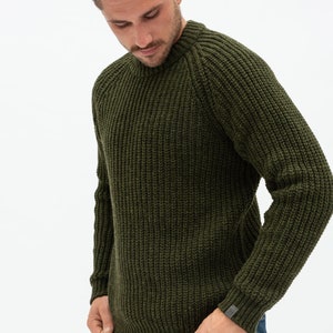 May include: A green knitted sweater with a ribbed texture. The sweater has a crew neck and long sleeves.