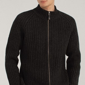 May include: A dark gray knitted zip-up cardigan with a high collar and ribbed texture.