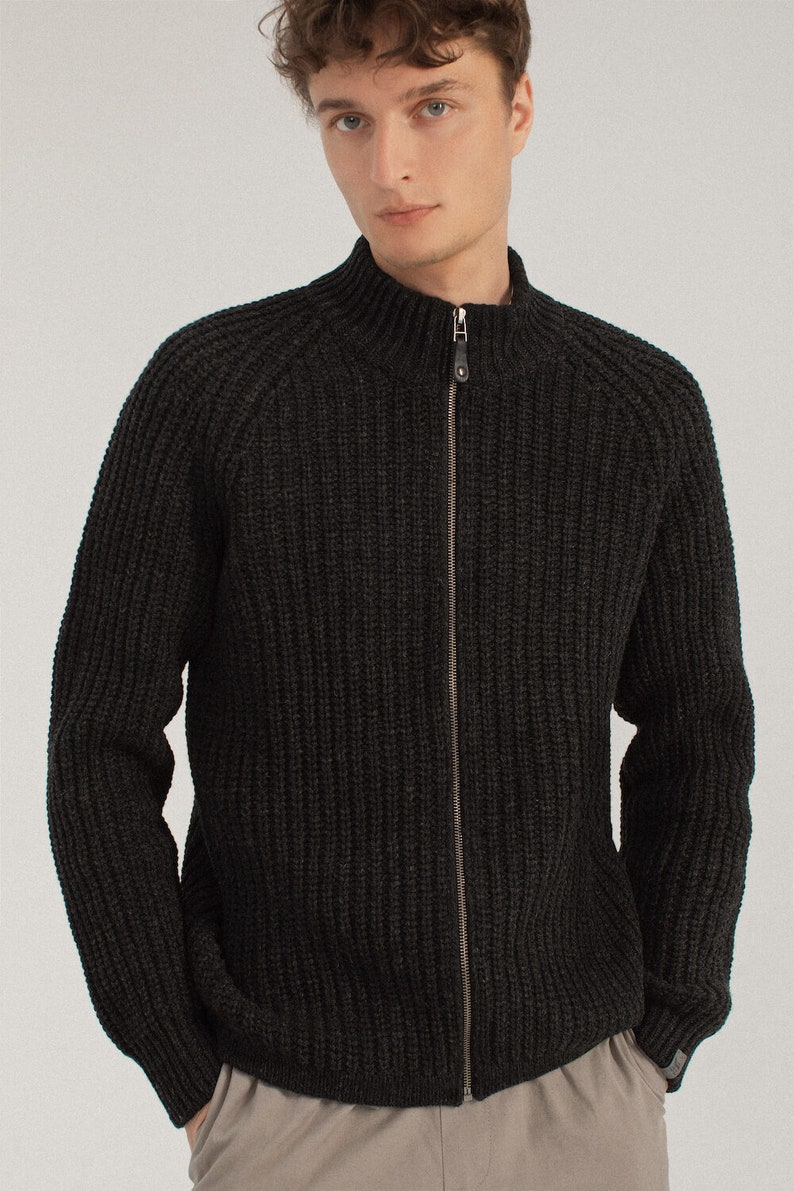 May include: A dark gray knitted zip-up cardigan with a high collar and ribbed texture.