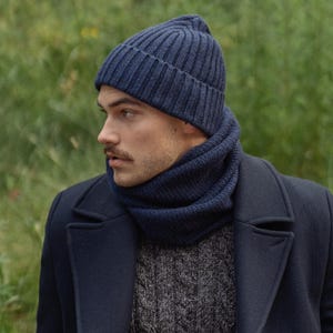 May include: A dark blue ribbed knit beanie and a matching dark blue ribbed knit neck warmer. The beanie features a folded cuff design, and both items are crafted from a thick, textured yarn, providing a cohesive look when worn together.