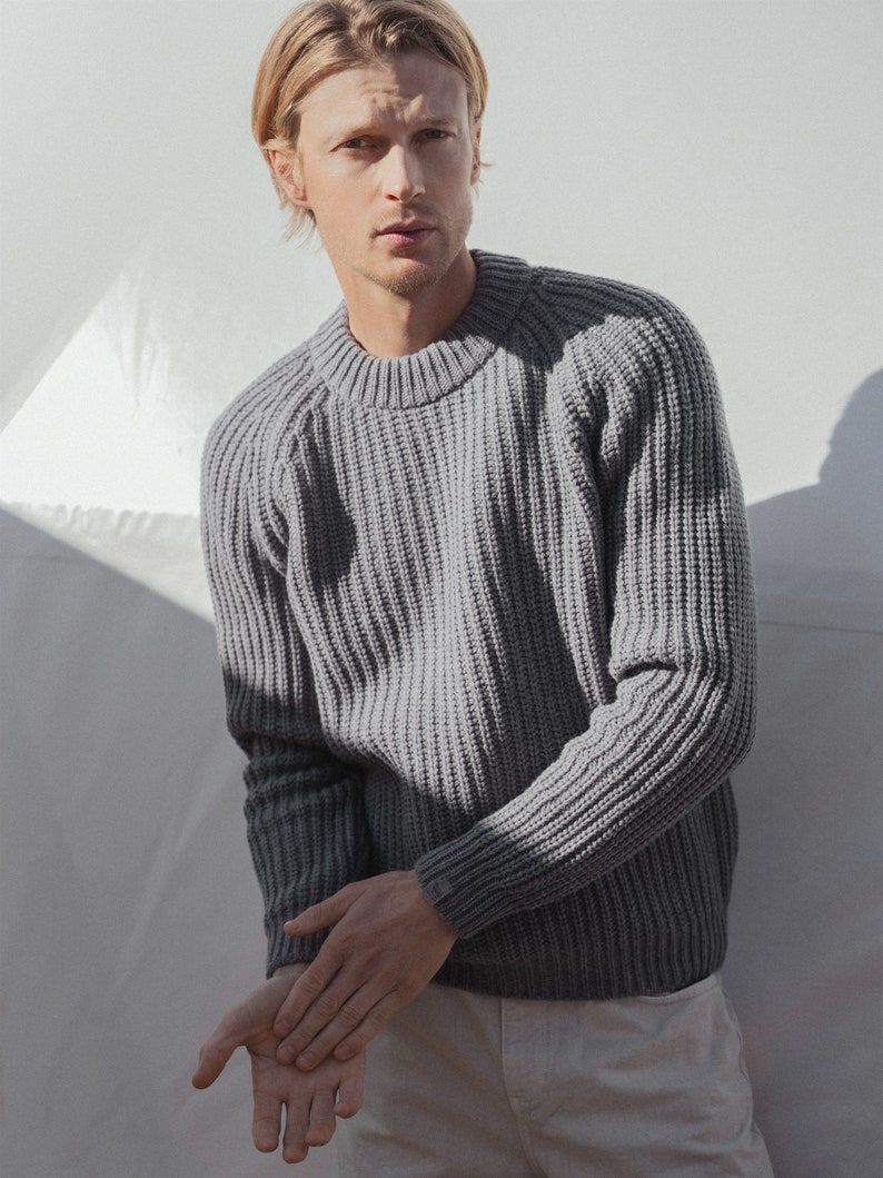 May include: A gray ribbed knit sweater with a crew neck.