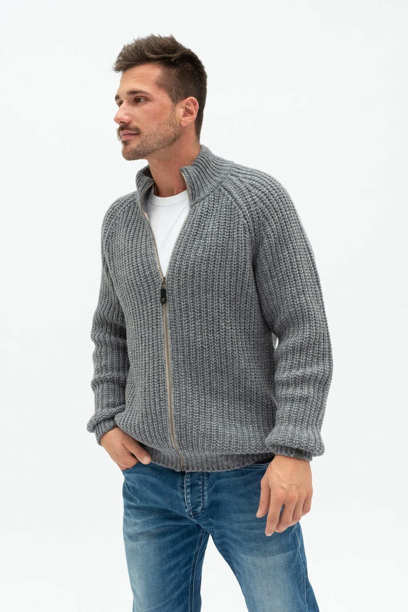 May include: A gray knitted zip-up cardigan with a high collar and ribbed texture.
