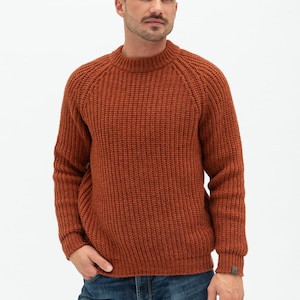 May include: A rust-colored knitted sweater with a round neckline and long sleeves.