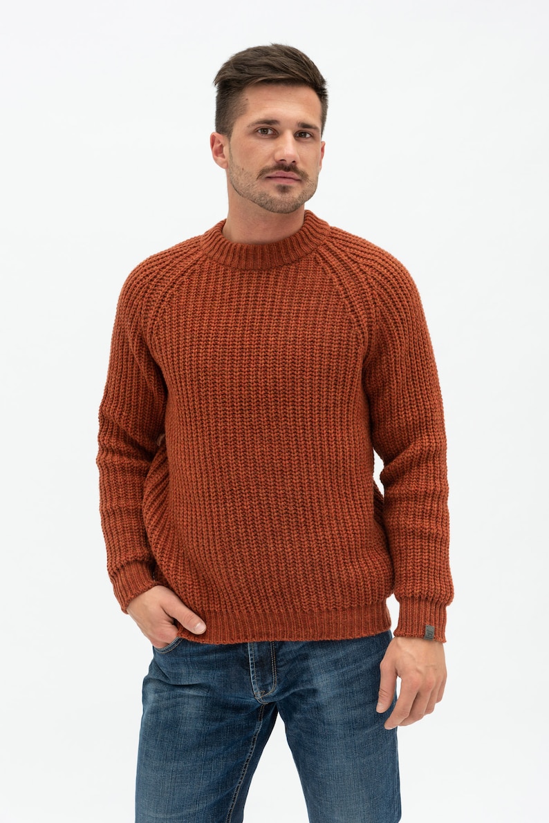 May include: A rust-colored knitted sweater with a round neckline and long sleeves.