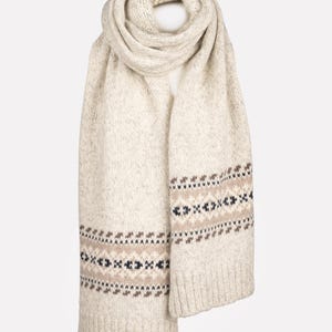 May include: Cream-colored knitted scarf with a geometric pattern in brown, black, and navy blue. The scarf is folded and draped, showcasing its texture and design. A cozy winter accessory.