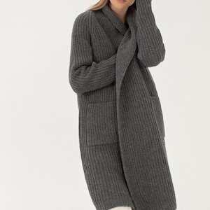 Pu&ograve; includere: Un cardigan lungo di colore grigio con collo a scialle e due tasche. Il cardigan &egrave; realizzato in un tessuto morbido e lavorato a maglia.