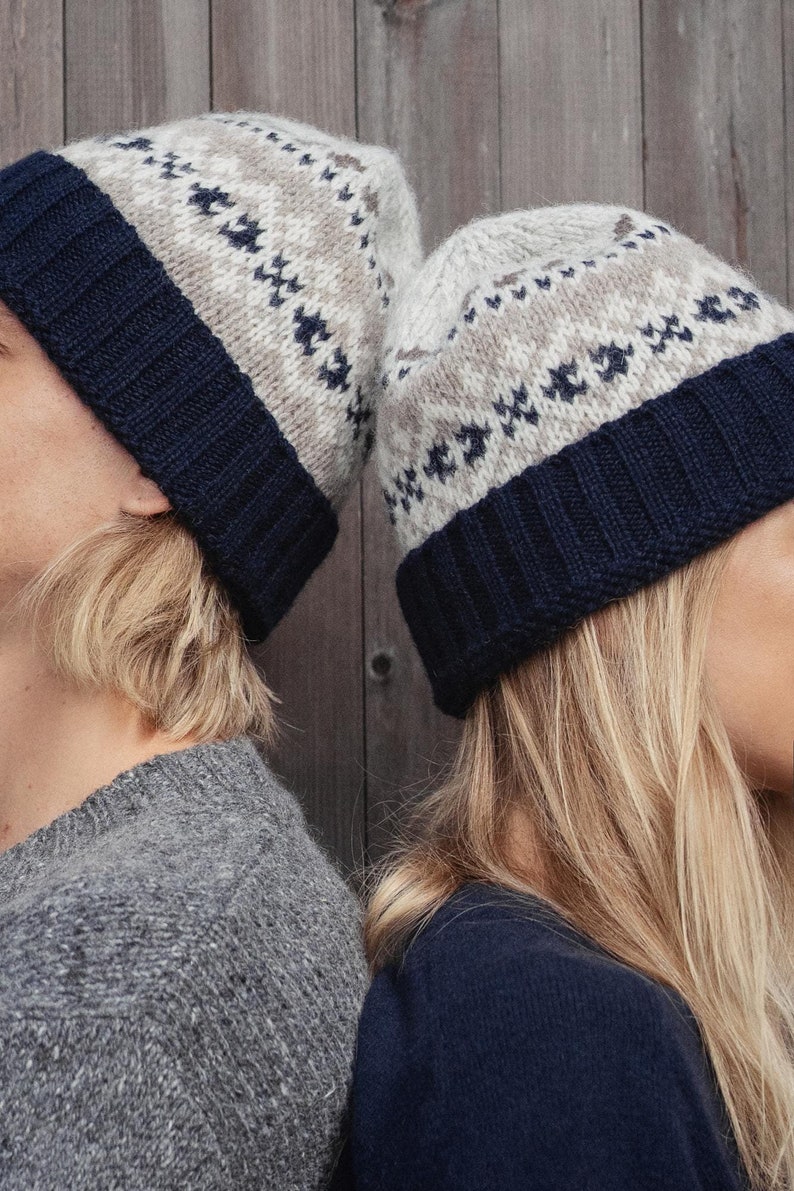 May include: Two people wearing matching knit hats with a white and brown geometric pattern and a navy blue brim. The hats are worn on their heads and the people are facing away from the camera.
