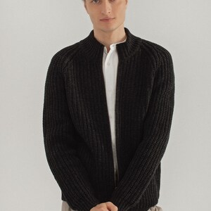 May include: A black knitted zip-up cardigan with a stand-up collar.
