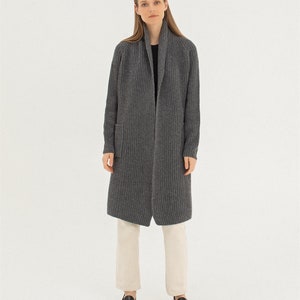 Pu&ograve; includere: Un cardigan lungo di colore grigio con collo a scialle e una tasca a toppa sul lato sinistro. Il cardigan &egrave; realizzato in un tessuto morbido e lavorato a maglia.