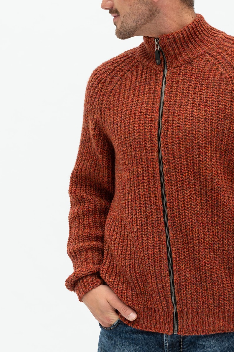 Pu&ograve; includere: Un cardigan di maglia color ruggine con chiusura a zip. Il cardigan ha un motivo a maglia testurizzato e un collo alto.