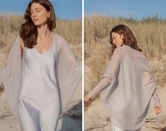 May include: A light gray knitted cardigan with a draped, open front and long sleeves. The cardigan is made of a soft, lightweight fabric and is perfect for layering.