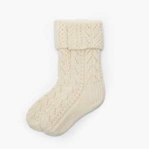 May include: A pair of white knitted socks with a lacy pattern. The socks are folded down at the top, revealing the intricate design.