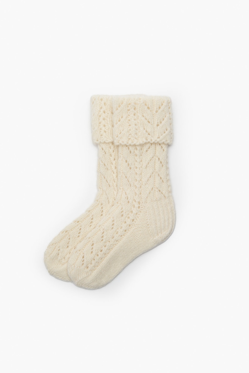 May include: A pair of white knitted socks with a lacy pattern. The socks are folded down at the top, revealing the intricate design.