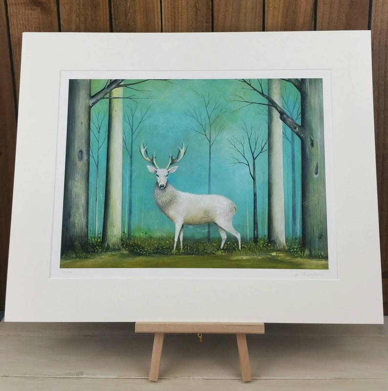 Pode incluir: Um veado branco est&aacute; em uma floresta com um fundo azul-esverdeado. O veado tem grandes chifres e est&aacute; rodeado de &aacute;rvores com galhos nus. A pintura &eacute; emoldurada com uma moldura branca.