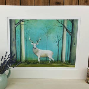 Pode incluir: Um veado branco est&aacute; em uma floresta com um fundo azul-esverdeado. O veado est&aacute; rodeado de &aacute;rvores com troncos brancos e folhas verdes. O veado est&aacute; olhando para a esquerda da imagem.
