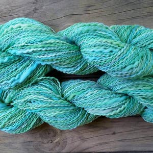 Green merino handspun wool yarn, in greens, aqua and a little grey. Softly plied with a fine polyester thread, giving texture & shine