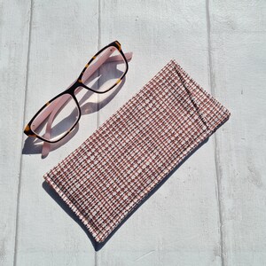 May include: A brown and pink tortoiseshell eyeglasses case with a white and brown checkered pattern.