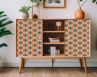 May include: A mid-century modern style cabinet with two doors and three shelves. The cabinet is made of wood and has a light brown finish. The doors are decorated with a geometric pattern in shades of orange, green, and beige. The cabinet is sitting on a white floor.