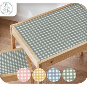 May include: A child's wooden table and stool set with a green and white gingham pattern. The natural wood frame supports the gingham tabletop. Includes colour swatches of pink, yellow, blue, and green gingham.