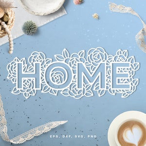 May include: White paper cut-out design of the word "HOME" surrounded by floral details on a light blue background. The design includes EPS, DXF, SVG, and PNG file formats.