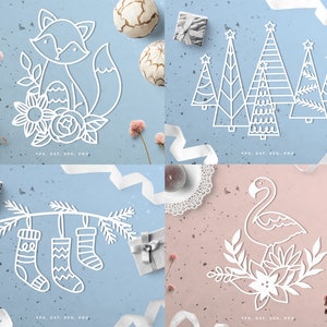May include: Four white paper cutouts on a blue and pink background. The cutouts include a fox with flowers, Christmas trees, hanging stockings, and a flamingo with flowers. The bottom of each cutout has the text "EPS, DXF, SVG, PNG."