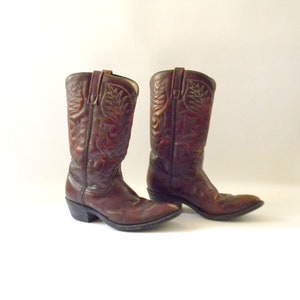 May include: A pair of brown leather cowboy boots with intricate stitching and a pointed toe.