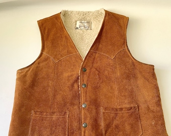 May include: A brown suede vest with a shearling lining. The vest has a button closure and two pockets. The label reads "Wool-Liner Jock Kay".