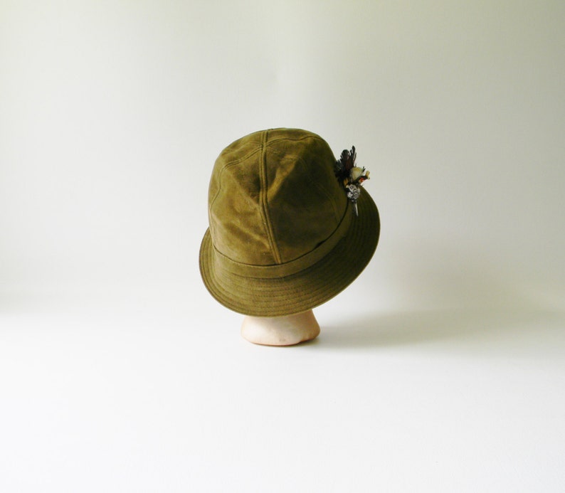 May include: A green suede bucket hat with a small floral embellishment on the side.