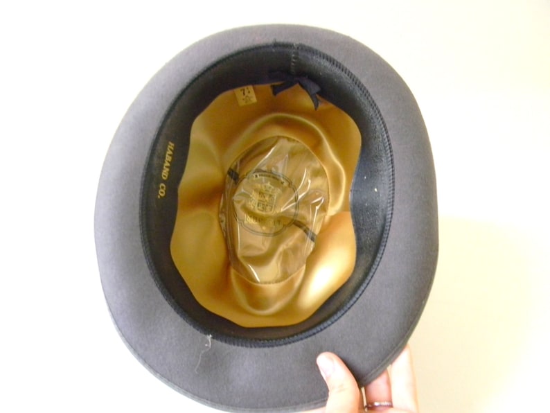 May include: A gray felt fedora hat with a gold satin lining. The hat has a label inside that reads "Harland Co."
