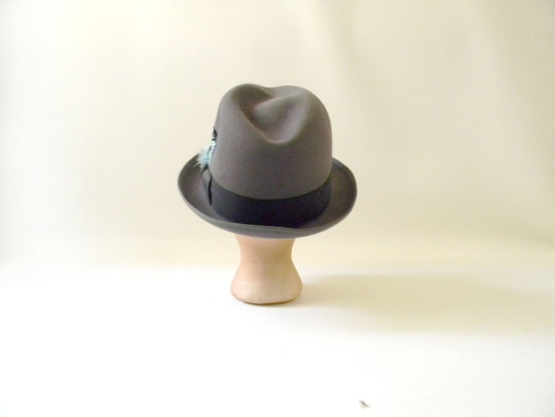 May include: A gray fedora hat with a black band and a small blue feather accent.