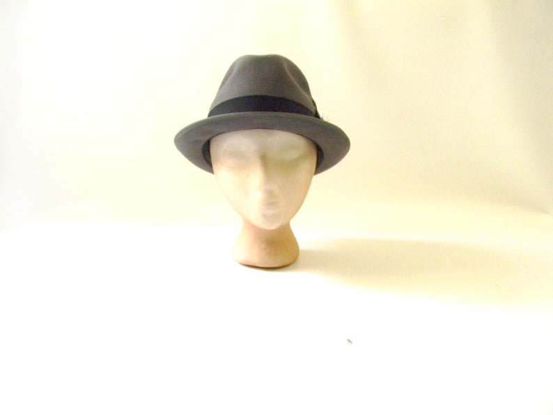 May include: A gray fedora hat with a black band around the crown. The hat is on a mannequin head.