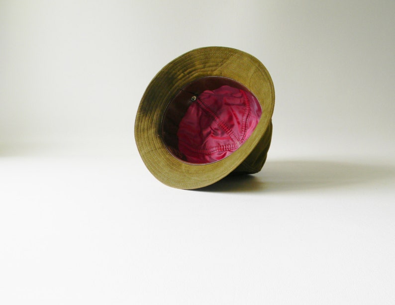 May include: A green and brown hat with a pink lining. The hat is turned inside out, showing the lining.