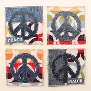 May include: Four fabric coasters with a peace sign design. Each coaster has a different pattern of colorful fabric with a denim peace sign in the center. Two of the coasters have the word "PEACE" printed in white on them.