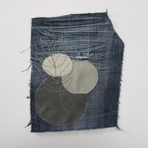 Peut inclure: Un morceau de tissu en jean avec un motif de branche et trois cercles dans des tons de gris et beige.