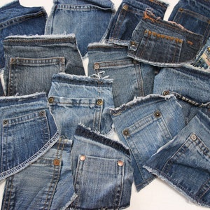 Può includere: Una collezione di ritagli di tessuto denim con bordi sfrangiati. I ritagli sono di varie tonalità di blu e hanno tasche.