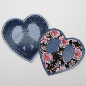 Könnte beinhalten: Zwei herzförmige Patches aus Jeans mit ausgeschnittenem Peace-Zeichen. Ein Patch ist aus einfachem Jeans, der andere hat einen Blumendruck.