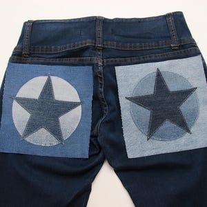 Könnte beinhalten: Eine dunkelblaue Jeans mit zwei großen, hellblauen Patches auf der Rückseite. Jeder Patch zeigt einen dunkelblauen Stern in einem Kreis.