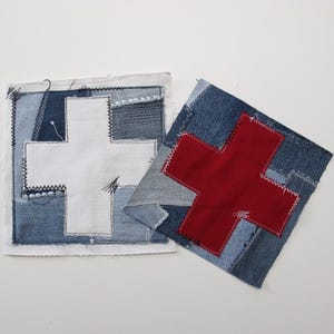 May include: Two denim patches with cross designs. One patch features a white cross on a patchwork denim background. The other patch has a red cross on a blue denim patchwork background. Both patches are square and have visible stitching.