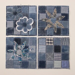Op de afbeelding: Vier denim vierkanten met patchwork achtergronden en appliquéd bloemmotieven. De bloemen zijn gemaakt van verschillende denim stoffen, waaronder effen en bedrukte stukken. De vierkanten zijn gerangschikt in een rasterpatroon op een witte achtergrond.