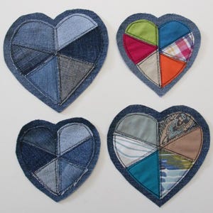 May include: Four denim heart-shaped coasters with different fabric patchwork designs. Each coaster features a variety of colors and patterns, including blue, green, red, orange, and brown.