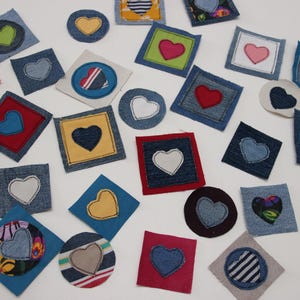 Puede incluir: Una colección de parches de corazón de mezclilla en varios colores y patrones. Los parches están cosidos con hilo de diferentes colores y presentan diferentes diseños, que incluyen corazones, flores y formas geométricas.