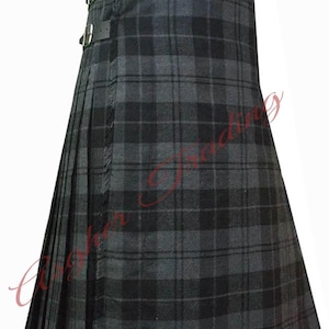 Könnte beinhalten: Ein plissierter Kilt mit einem dunkelgrauen und schwarzen Schottenkaro-Muster. Das Kleidungsstück verfügt über zwei schwarze Lederriemen mit silberfarbenen Metallschnallen an der Seite zum Verschließen. Der Stoff hat eine sichtbare Textur mit vertikalen Falten.