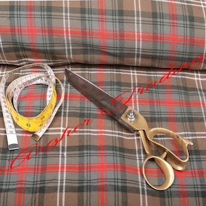 May include: A roll of plaid fabric in shades of brown, grey, red, and white. A yellow and white measuring tape and a pair of brass-handled scissors are on the fabric. The measuring tape shows measurements in centimetres.