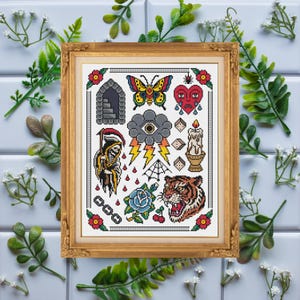 Peut inclure: Un motif de point de croix encadré présentant des éléments de style tatouage traditionnel, notamment un papillon, un cœur triste, la faucheuse, un nuage avec éclairs, une bougie, une toile d'araignée, une rose bleue et une tête de tigre.