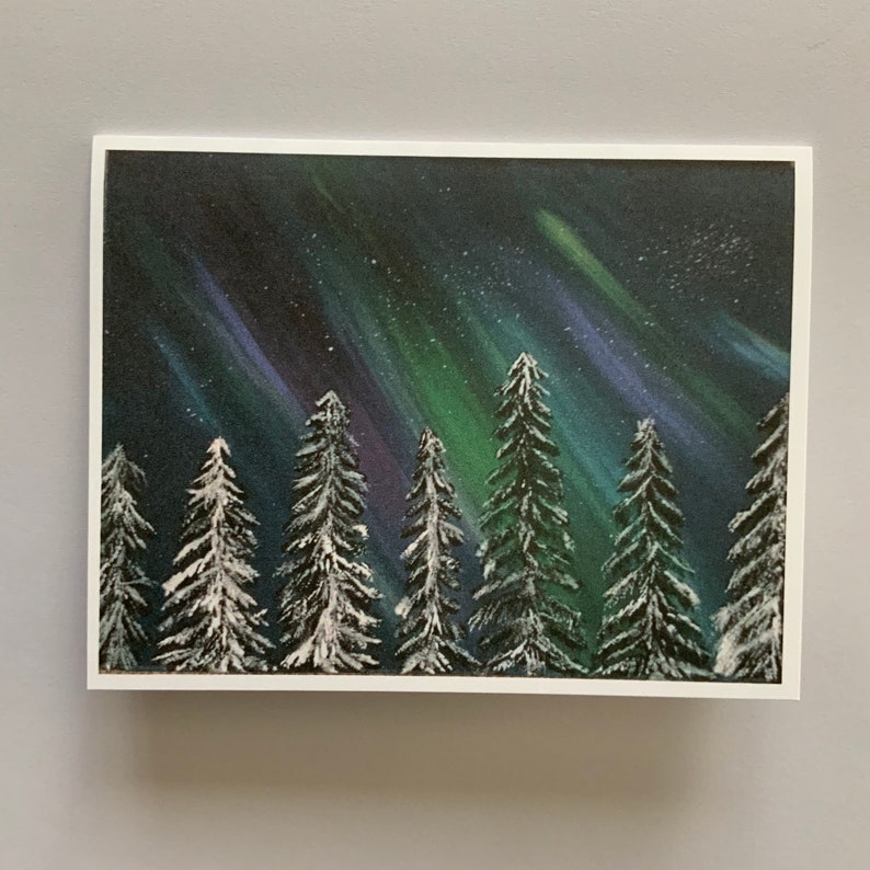 May include: A painting of a snowy forest with a vibrant green, blue, and purple aurora borealis in the night sky.