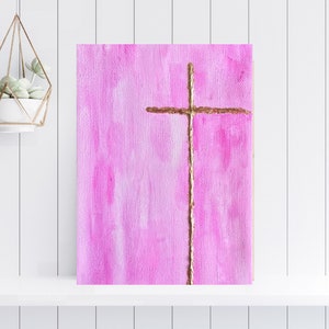 May include: A pink canvas painting with a gold cross in the center. The cross is painted with a textured, brushstroke effect.