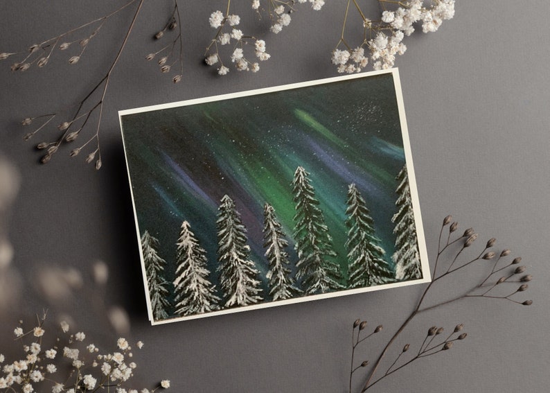May include: A painting of a snowy forest with a green and purple aurora borealis in the night sky.