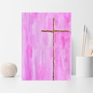 May include: A simple gold cross painted on a pink background. The cross is painted with a textured brushstroke.