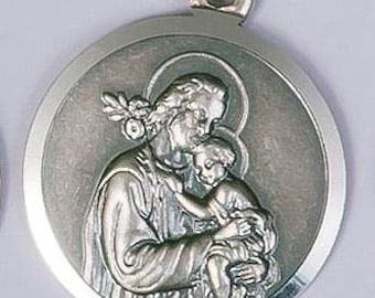 May include: Silver pendant featuring a detailed image of Saint Joseph holding the baby Jesus. The pendant is round and has a smooth, polished finish.
