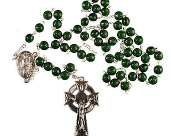 May include: Green wooden bead rosary with a silver Celtic cross pendant. The cross features a detailed design and a figure of Jesus Christ.